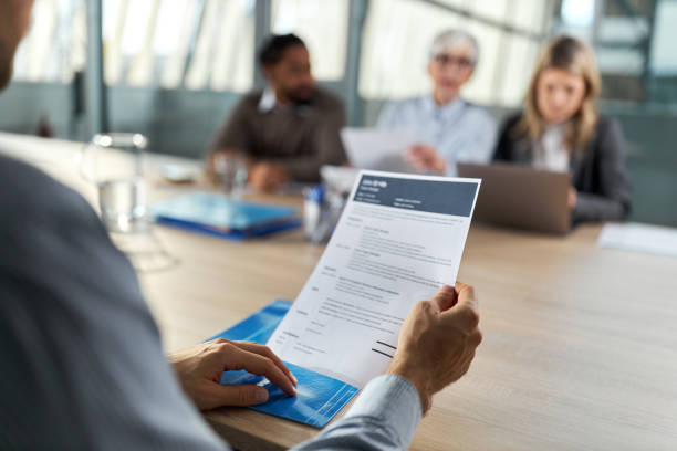 Close up of unrecognizable male candidate holding his CV during job interview in the office.